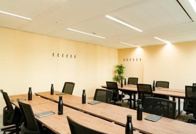 Training room with long wooden tables, black chairs, and individual water bottles.