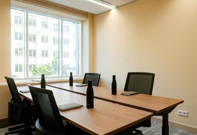 Small meeting room with a large window and wooden tables setup with notebooks.