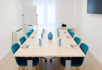 Modern conference room with a long rectangular table, blue chairs, and a whiteboard.