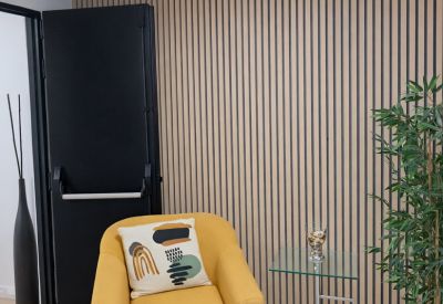 Breakout area with a yellow armchair, glass side table, and wood-slat feature wall.