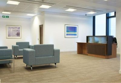 Spacious reception area with blue armchairs and a modern wooden front desk.