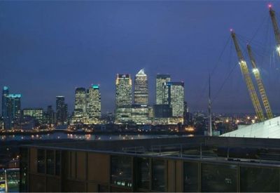 Dusk view of the illuminated city skyline across the water from a terrace.