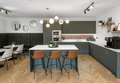 Modern kitchen and dining area with a large island and herringbone wood floors.