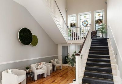 Grand entrance lobby featuring a sweeping staircase, wooden floors, and stained glass windows.