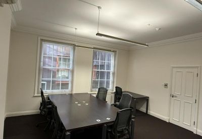 Boardroom with a large dark wood table, several mesh chairs, and white paneled door.
