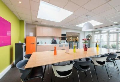 Spacious communal kitchen and dining area featuring a long wooden table and an orange retro fridge.