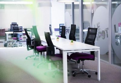 Coworking workspace with white desks and ergonomic black chairs with purple accents.