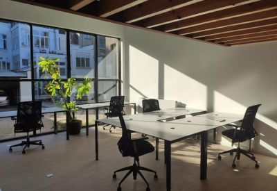 Open-plan office with multiple workstations and views of the surrounding urban greenery.