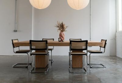 Bright dining area with a large light wood table and wicker cantilever chairs.