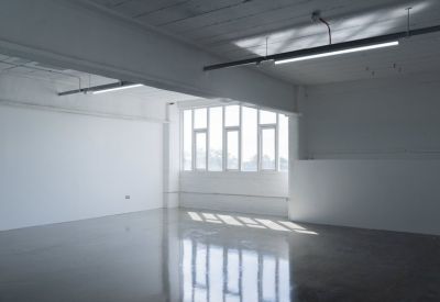 Spacious empty industrial studio with polished concrete floors and large windows.
