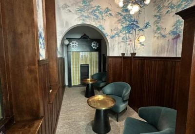 Stylish breakout space featuring teal velvet chairs, yellow stools, and a designer chandelier.