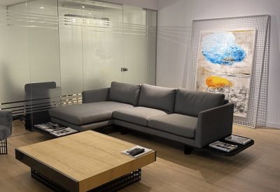 Lounge area featuring a grey sectional sofa, wooden coffee table, and colorful abstract art.
