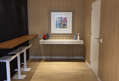 Minimalist hallway featuring a white console table, colorful vases, and wooden wall panels.