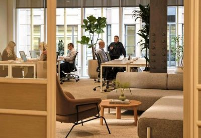Bright open-plan office with desks, lounge seating, and large windows.