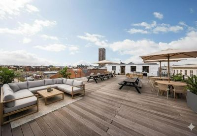 Spacious rooftop terrace with a large sectional sofa, picnic tables, and views over Copenhagen.