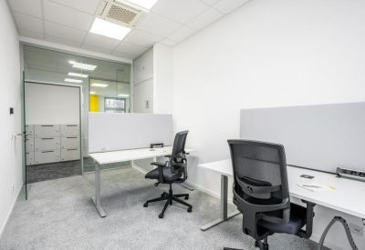 Bright shared office space with two white desks and ergonomic black chairs.