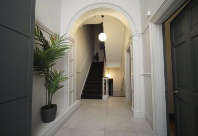 Entrance hallway at 62, Mount Street Lower, with a white archway, potted plant, and grand staircase.
