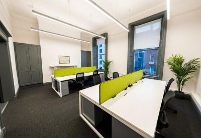 Bright open-plan office with white desks, lime green privacy screens, and large windows.