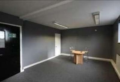 Small meeting room with a round wooden table and grey walls.