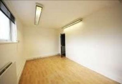 Empty private room with light wood flooring and bright white walls.