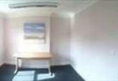 Bright private office featuring light-colored walls, a wooden table, and large windows.