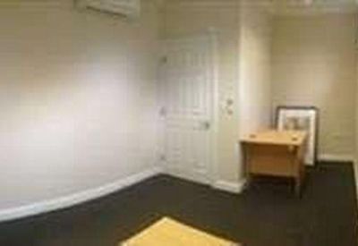 Small office space with dark carpeting, a wooden desk, and a white door.