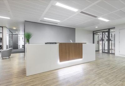 Minimalist reception desk with white and wood finishes, integrated lighting, and light wood floors.
