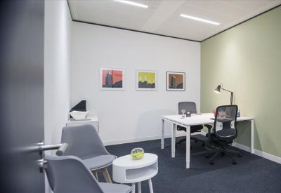 Private two-person office with a green feature wall, artwork, and a modern white desk.