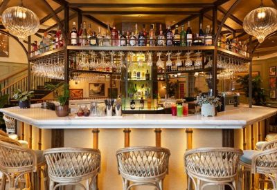 Circular marble-topped bar with woven stools and overhead bottle storage.