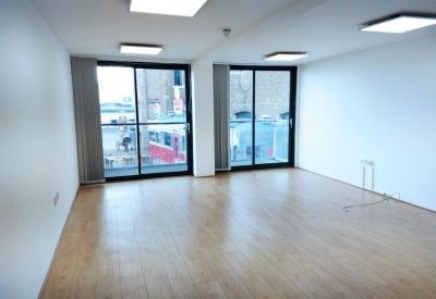 Spacious open-plan office with floor-to-ceiling sliding glass doors and natural light.