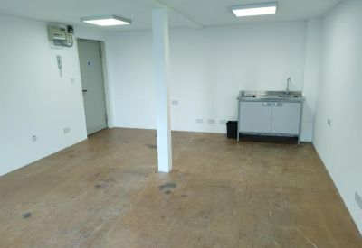 Communal kitchenette area with a simple grey sink unit and wood-effect flooring.