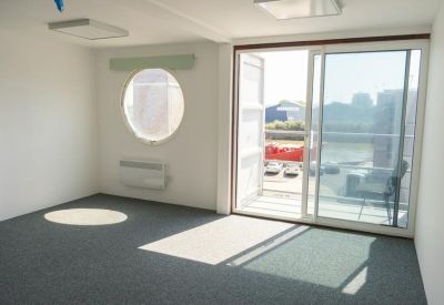 Bright workspace with a circular window and sliding glass door leading to a balcony.