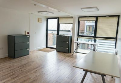 Open-plan workspace with wooden floors and dark grey storage units.