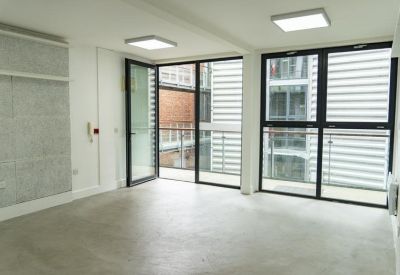Bright, empty office space with large windows and concrete-style wall panels.