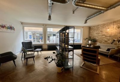 Spacious breakout lounge with parquet flooring, brick feature wall, and modern seating.