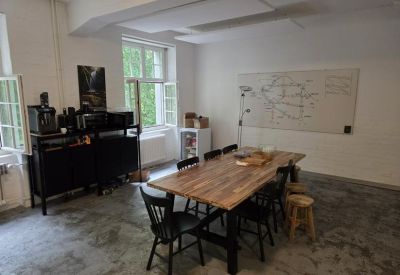 Meeting room with a large wooden table, whiteboard, and coffee station.
