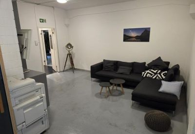 Lounge area with a dark sectional sofa, coffee tables, and a printer.