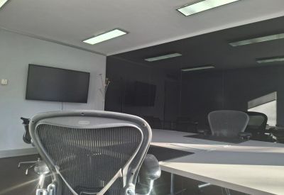 Modern meeting room featuring a large screen and ergonomic mesh chairs.