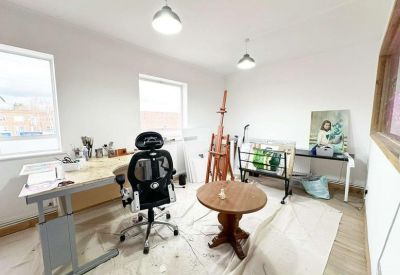 Artist studio room with an adjustable desk, ergonomic chair, and an easel.
