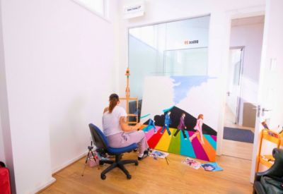 Private art studio space with a person painting on a large canvas near a window.