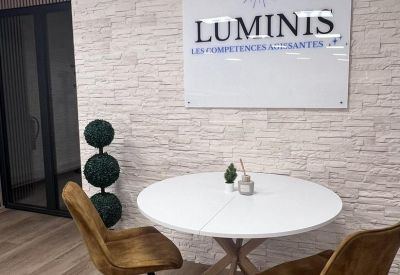 Small reception area with a white round table, tan chairs, and branded logo wall.
