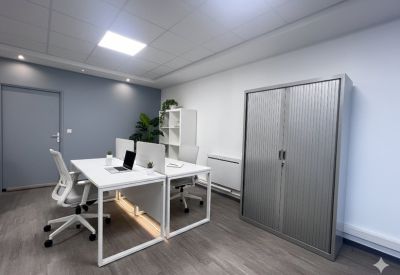 Modern office with white desks, ergonomic chairs, and a grey storage cabinet.