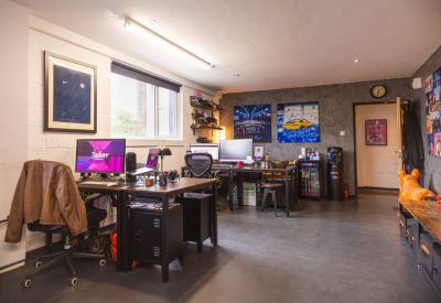 Modern workspace with multiple monitors, framed artwork, and a dark feature wall.
