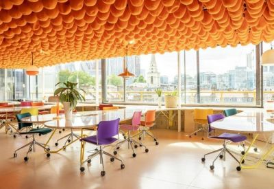 Spacious sunlit communal workspace with a textured orange ceiling and colorful chairs at 68-80, Hanbury Street.