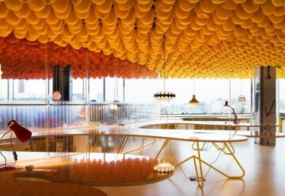 Open-plan workspace featuring a unique yellow bubble-textured ceiling and curved communal desks.