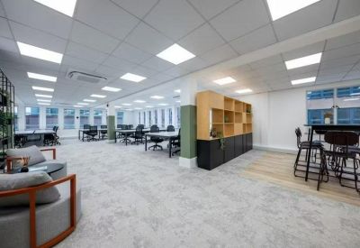 Spacious open-plan office with white pillars and several modern workstations.