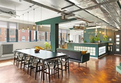 Spacious communal dining area with a long black table, wooden floors, and green feature walls.