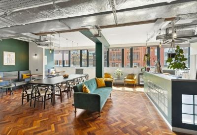 Bright lounge area with a teal velvet sofa, chevron wood flooring, and industrial ceilings.