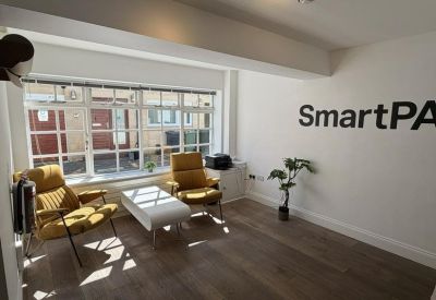 Bright breakout area with yellow armchairs, a white coffee table, and a green plant.