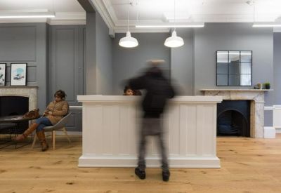 Reception area with a white paneled desk and a classic feature fireplace.